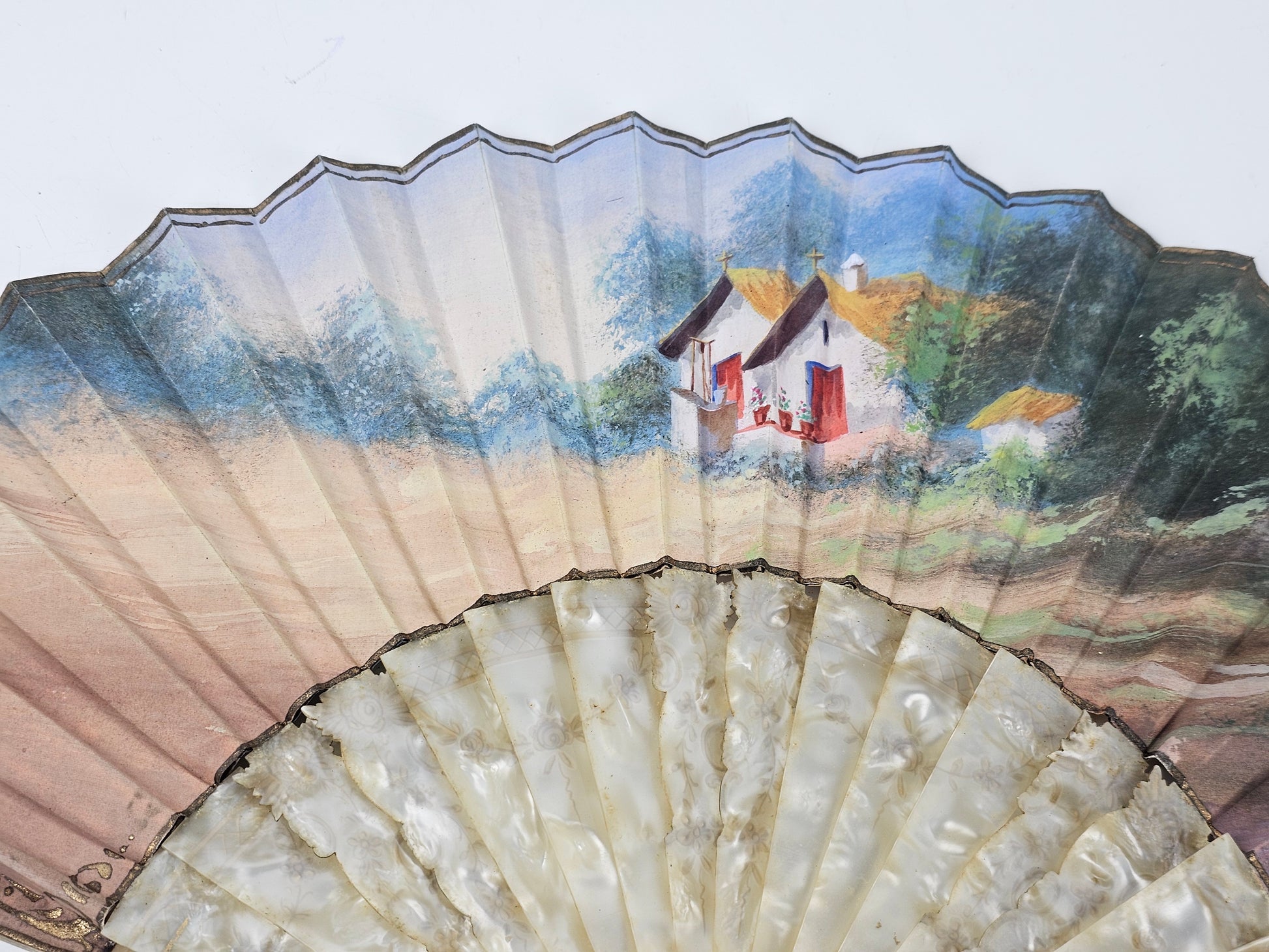 Handheld fan with a scenic painting of a house and landscape