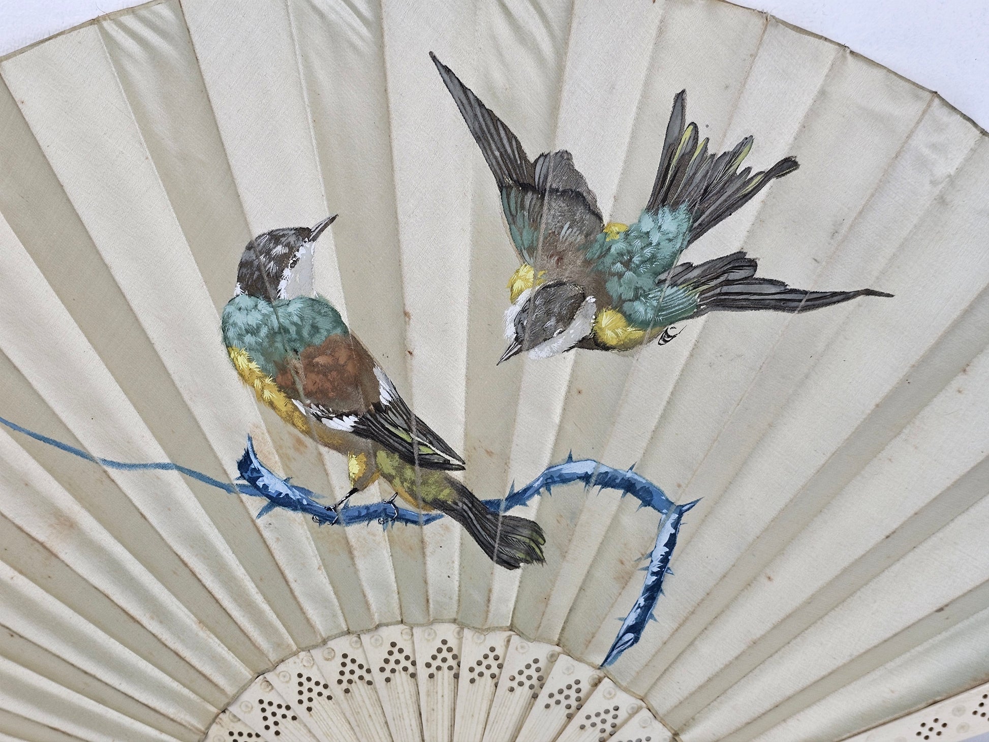 Decorative fan with painted birds on a off-white background