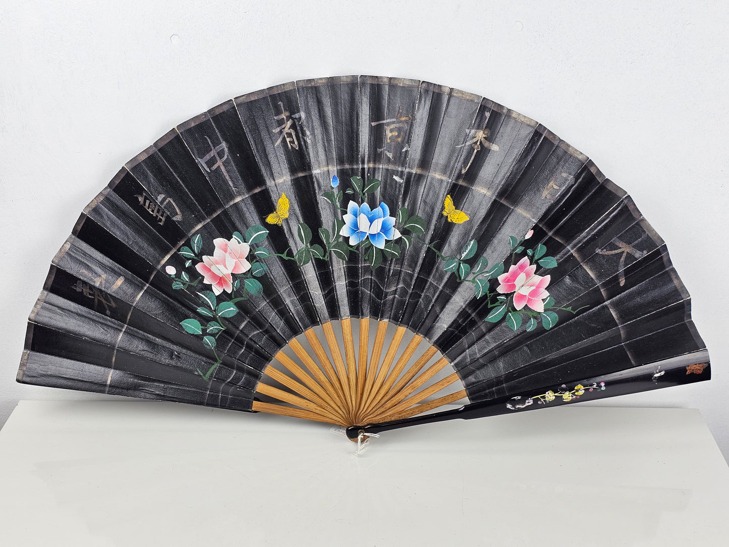vintage black fan with floral designs and butterflies on a black background