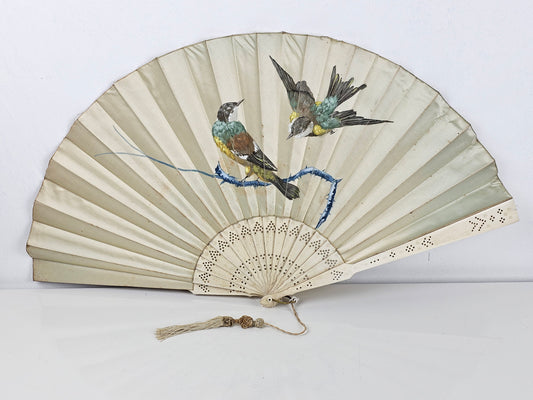 Handheld fan with bird design on a white background